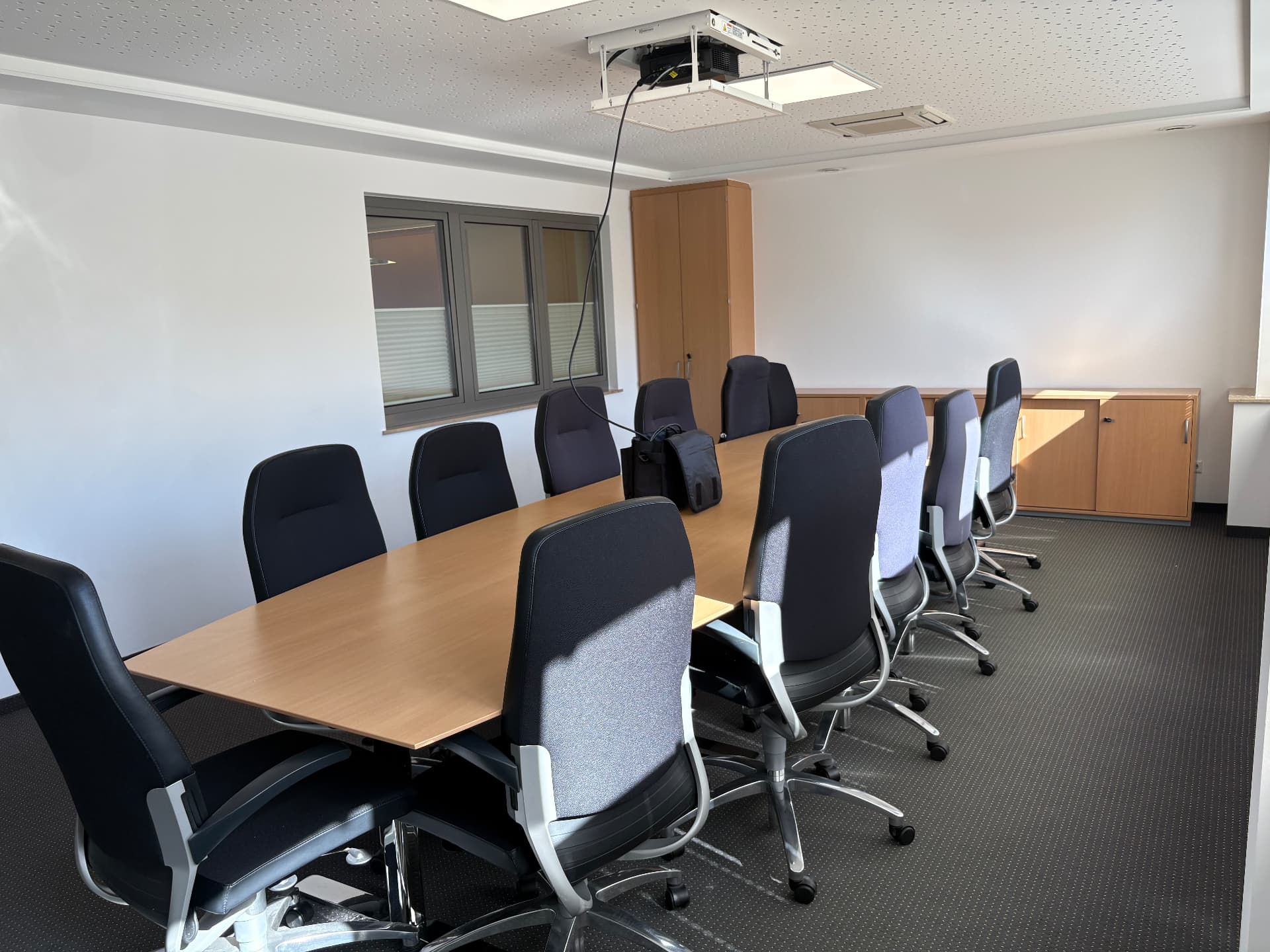 Großer Konferenztisch, vorhandene Bestuhlung und Deckenprojektor