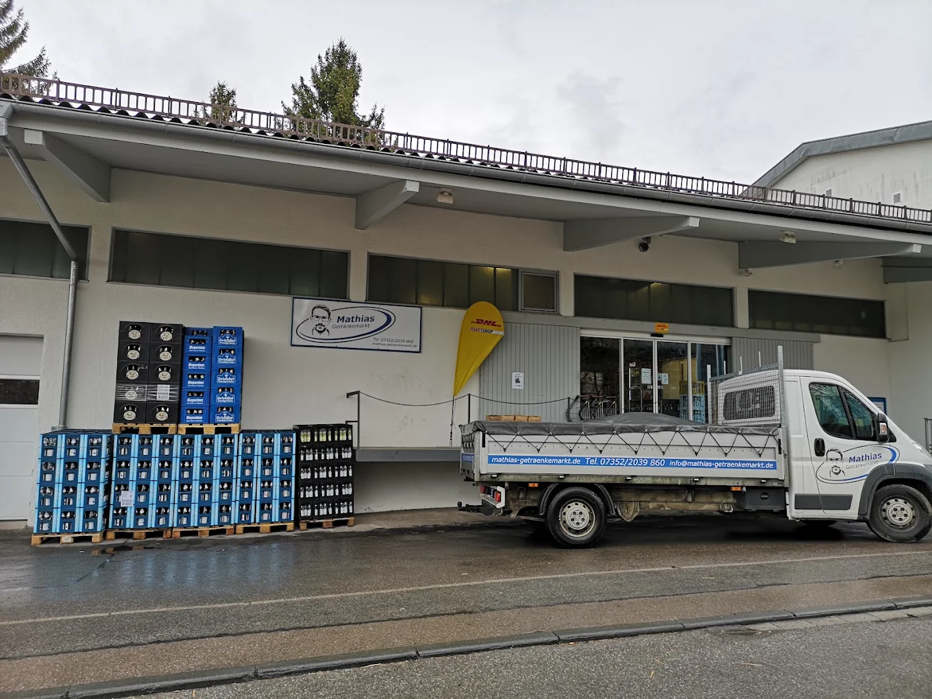 Eingang des Mathias Getränkemarkts im hinteren Gebäudeteil mit Schild und Lieferfahrzeug